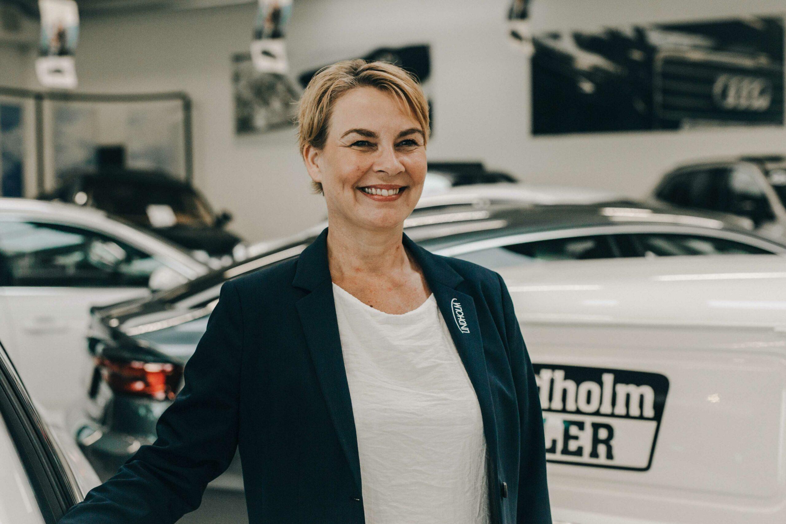 Profilbillede af leasingkoordinator Lotte Schou hos Lindholm Biler i biludstilling med biler i baggrunden