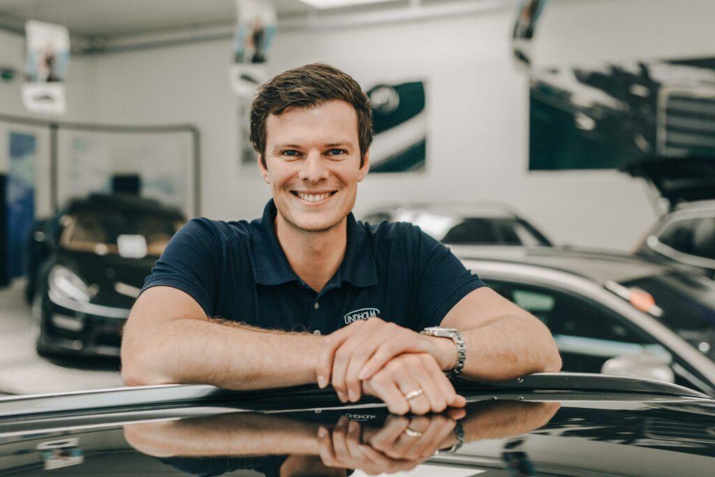 Profilbillede af partner og leasingchef Thomas Jakobsen hos Lindholm Biler i biludstilling med biler i baggrunden